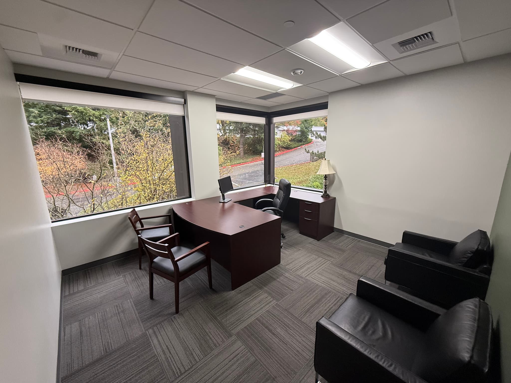 Large corner office with floor-to-ceiling windows and skyline views
